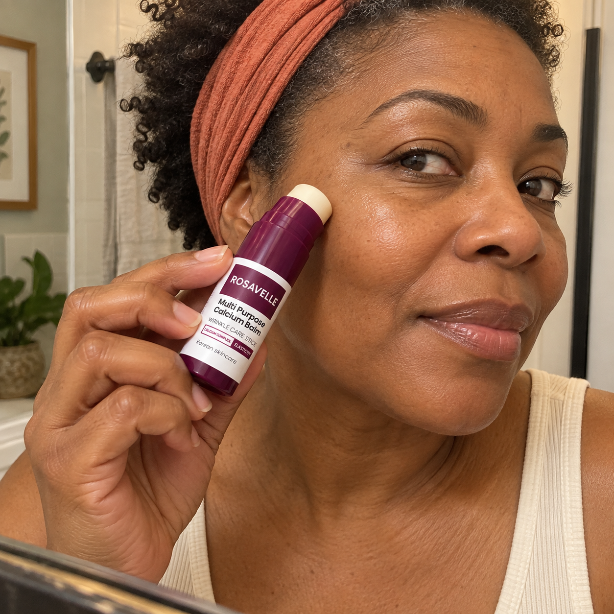 Woman using Rosavelle balm by a mirror