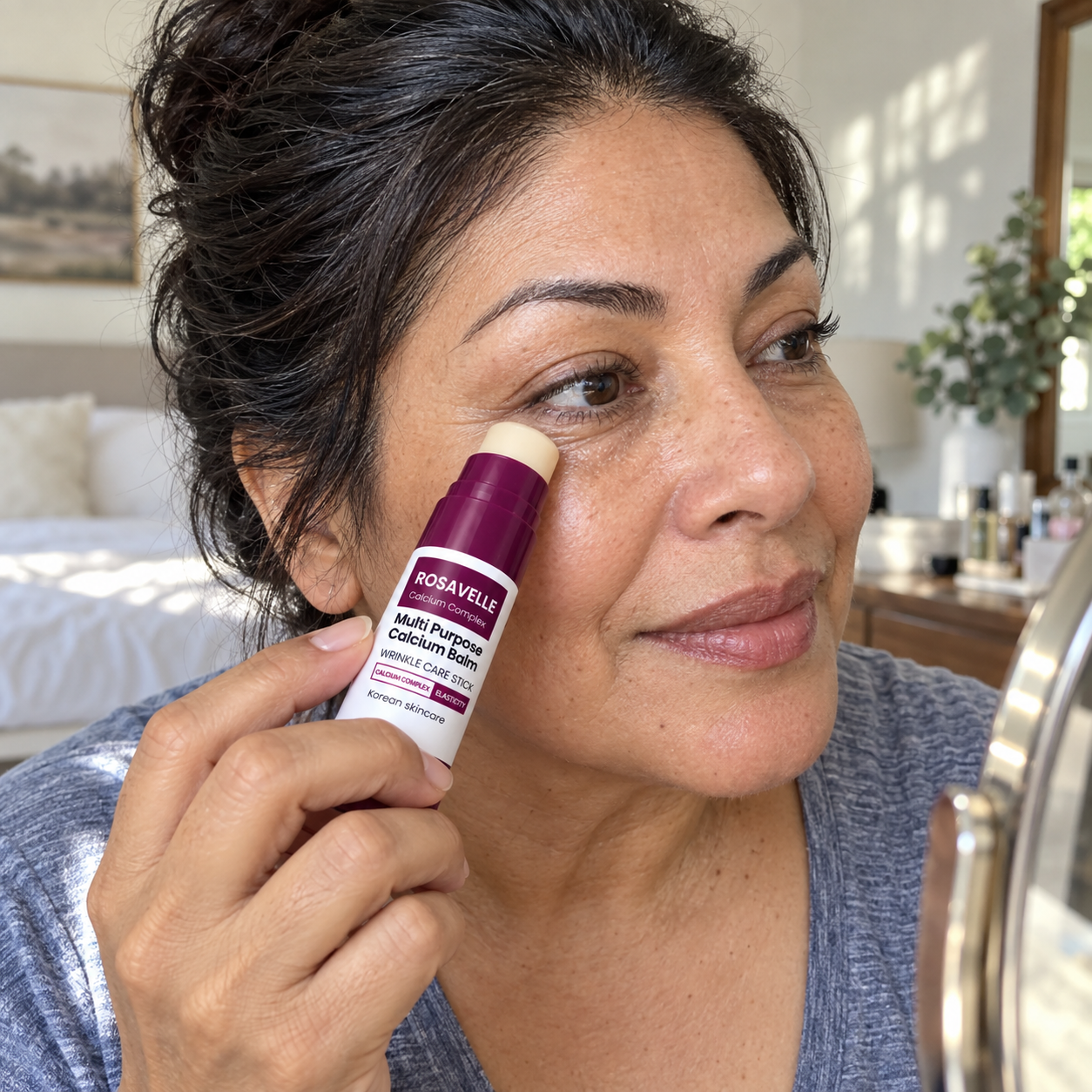 Woman applying Rosavelle balm beside a vanity