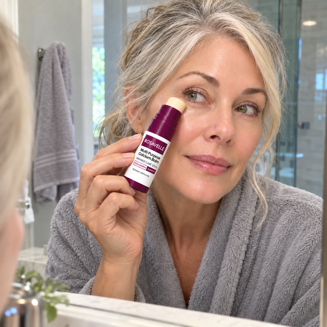 Woman applying Rosavelle balm under her eye in a bathroom